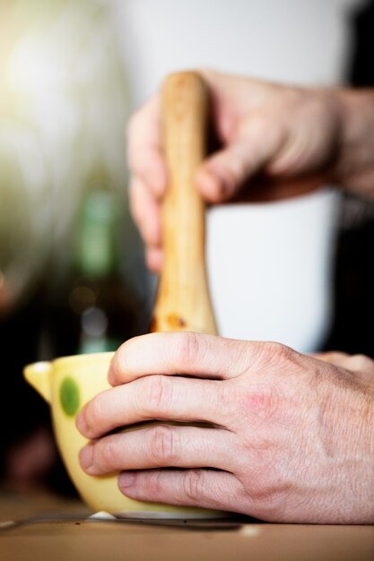 Hombre cocinando en una cocina casera, se mezcla en un mortero