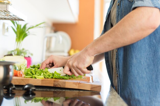 Hombre cocinando y cortando verduras para el almuerzo