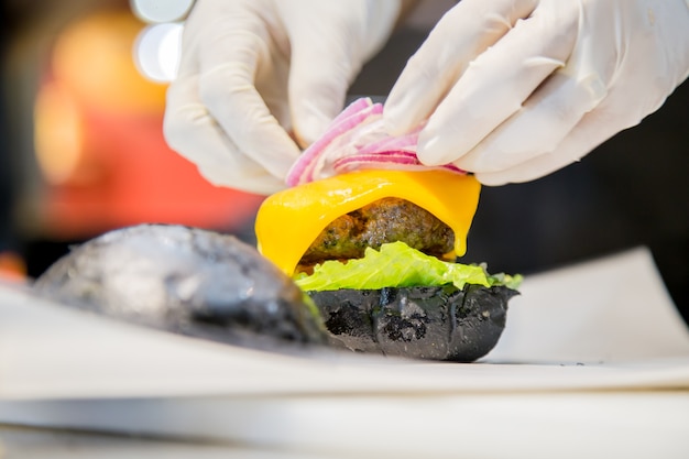 hombre cocinando una deliciosa hamburguesa de carne en la cocina rústica