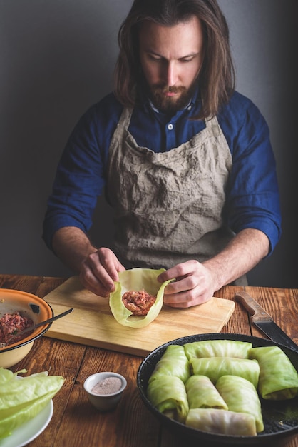 Hombre cocinando rollos de repollo rellenos con carne molida