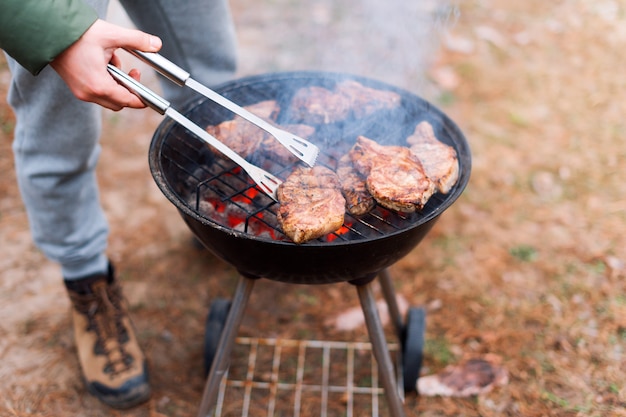 Hombre cocinando, solo manos, está asando carne o filete para un plato. deliciosas carnes a la parrilla. barbacoa fin de semana. enfoque selectivo.