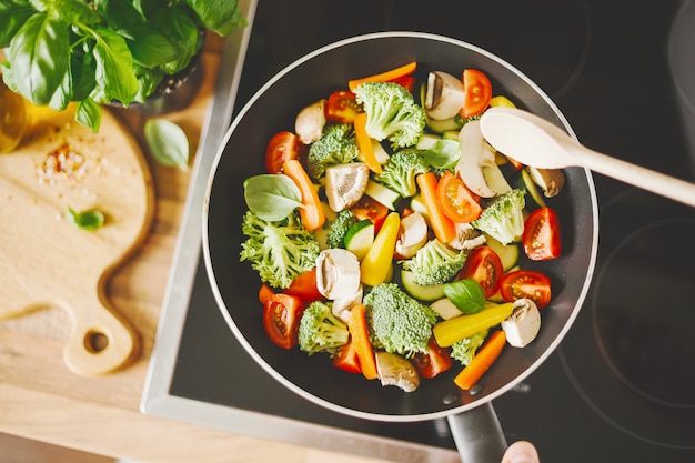 Hombre cocinando verduras frescas en la sartén