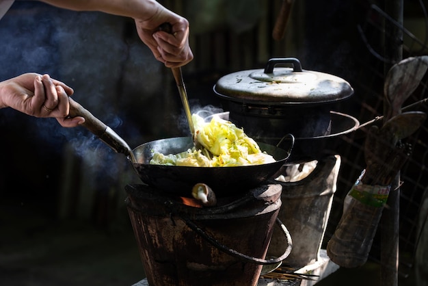 El hombre cocinando verduras en una sartén en una estufa vintage cocinando con leña para cocinar solo para comer en casa