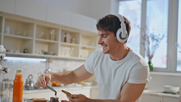 Foto hombre cocinero bailando con auriculares cantando su canción favorita en la cocina de cerca