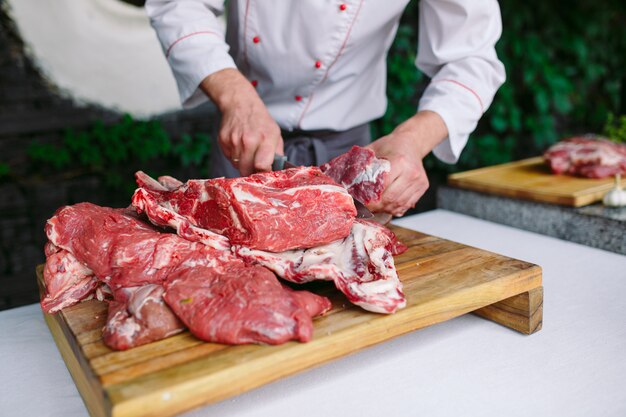 Un hombre cocinero corta la carne con un cuchillo en un restaurante.