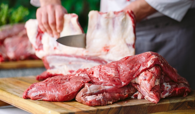 Un hombre cocinero corta la carne con un cuchillo en un restaurante.