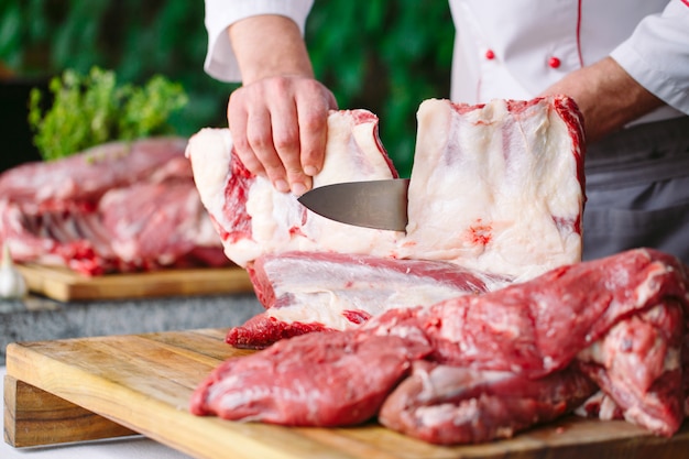 Un hombre cocinero corta la carne con un cuchillo en un restaurante.