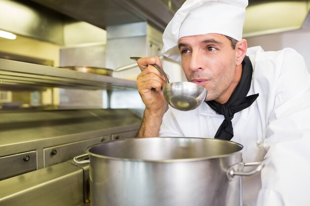 Hombre cocinero degustación de comida en la cocina