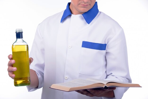 Hombre cocinero con libro de recetas y una botella de aceite.