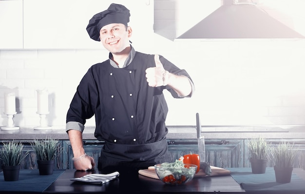 Hombre cocinero preparando comida en la mesa de la cocina de verduras