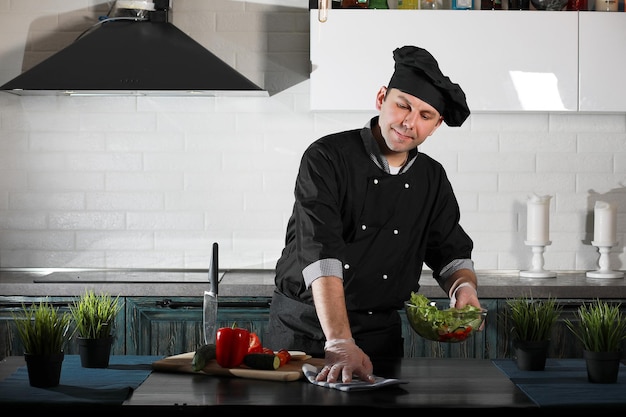 Hombre cocinero preparando comida en la mesa de la cocina de verduras