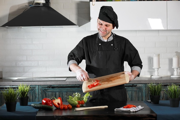 Hombre cocinero preparando comida en la mesa de la cocina de verduras