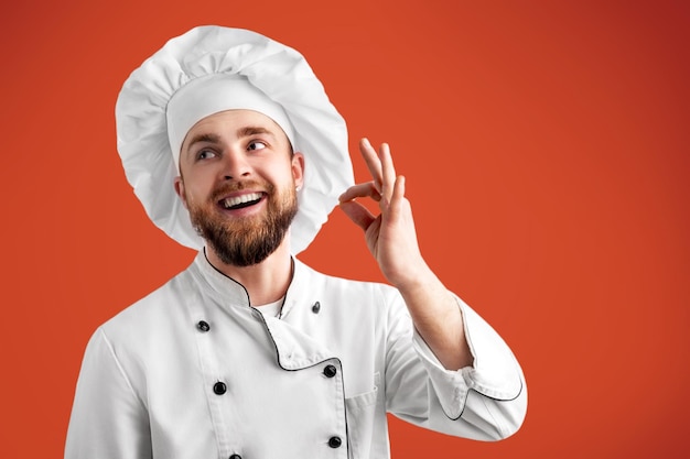 Hombre cocinero profesional que muestra el signo de delicioso. Chef de sexo masculino en uniforme blanco con signo perfecto.