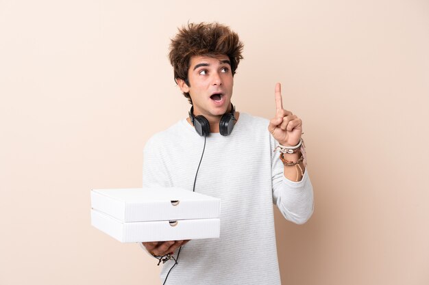 Hombre cogiendo cajas de pizza sobre pared aislada