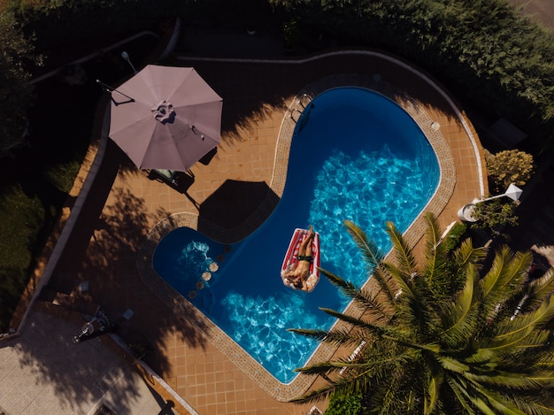 Hombre en colchón flotante en la piscina de una villa