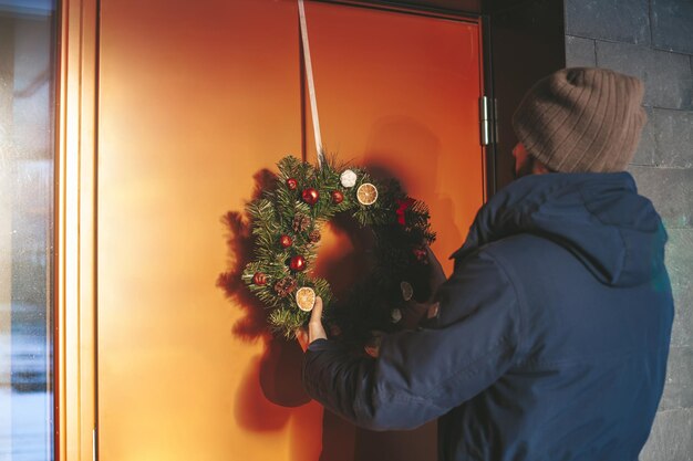 Hombre colgando la corona de Navidad en la puerta