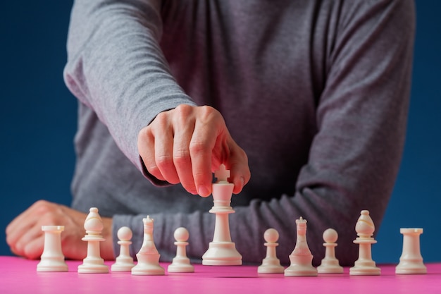 Hombre colocando pieza de ajedrez rey blanco delante de las otras figuras