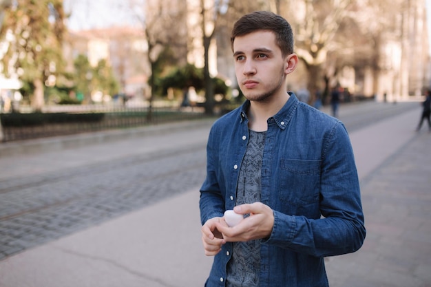 El hombre colocó sus auriculares inalámbricos. Un hombre guapo con camisa azul se para en el centro de la ciudad.