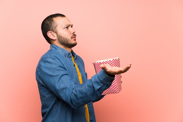 Hombre colombiano con palomitas aislado rosa