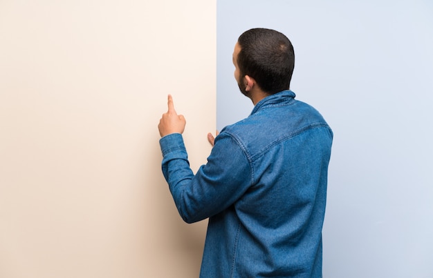 Hombre colombiano sosteniendo un cartel vacío apuntando hacia atrás con el dedo índice.