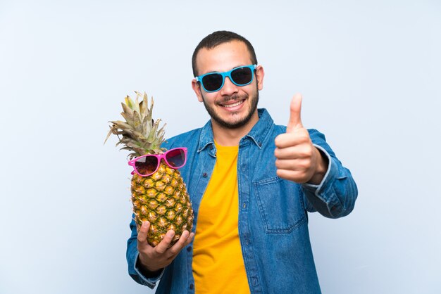 Hombre colombiano sosteniendo una piña con gafas de sol dando un pulgar arriba gesto y sonriendo