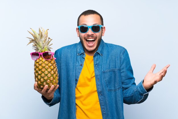 Hombre colombiano sosteniendo una piña con gafas de sol con sorpresa y expresión facial conmocionada