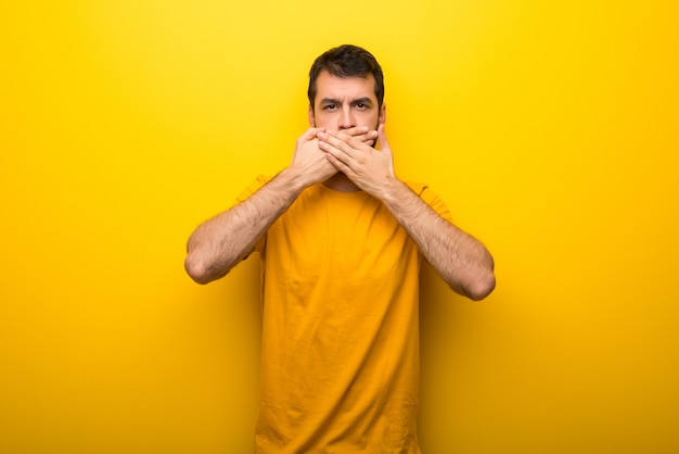 Hombre en color amarillo vibrante aislado que cubre la boca con las manos por decir algo inapropiado