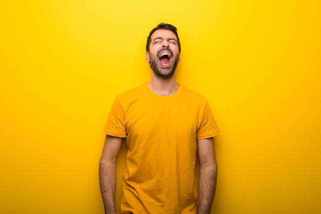 Hombre en color amarillo vibrante aislado que grita al frente con la boca abierta