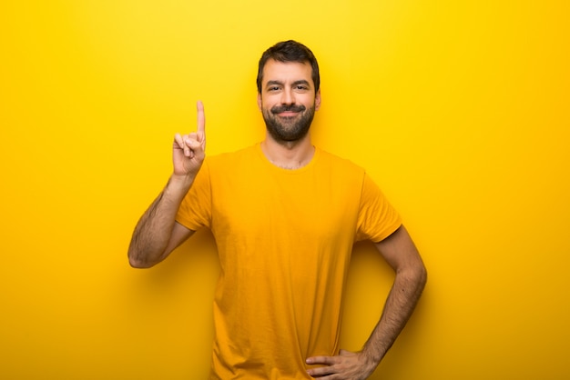 Hombre en color amarillo vibrante aislado que muestra y levanta un dedo en señal de lo mejor