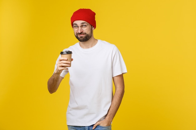 Hombre en color amarillo vibrante aislado tomando un café en una taza de papel para llevar y sonriendo porque comenzará bien el día.