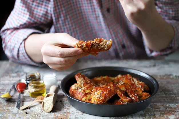 El hombre come alitas de pollo.