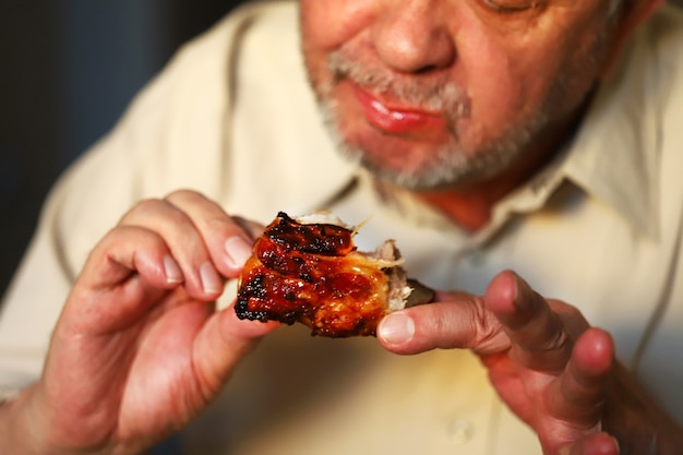 Un hombre come costillas de cerdo al horno con las manos. El hombre come carne. Comida chatarra. Carne frita, conceragen.