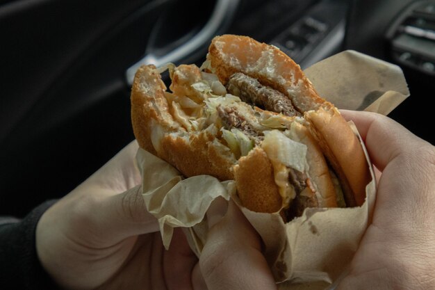 un hombre come una hamburguesa en un coche