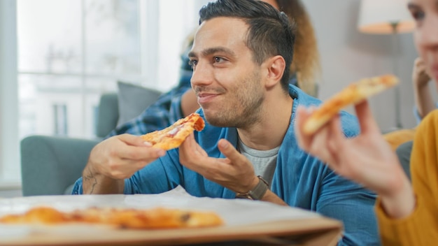 Un hombre come pizza con un trozo de pizza.