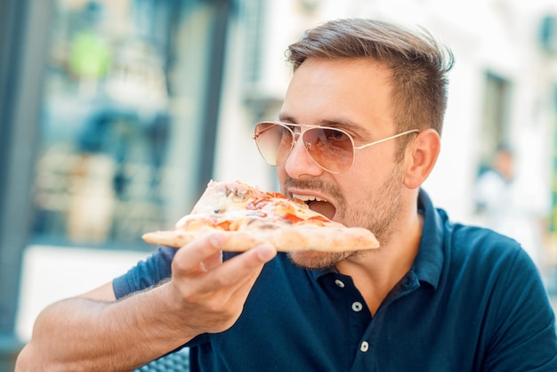 Hombre comiendo bocadillos de pizza al aire libre