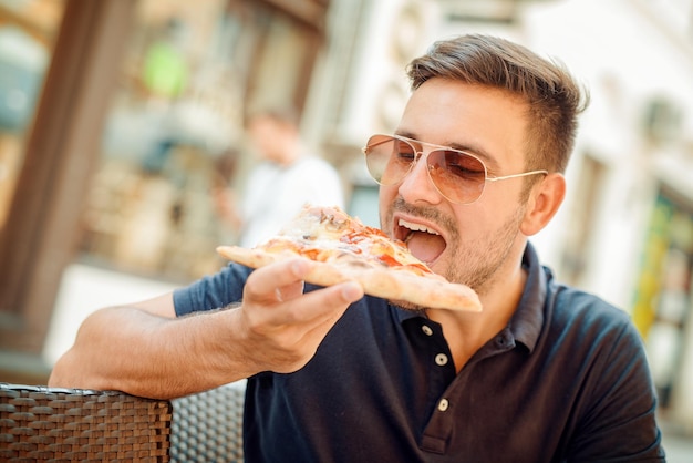 Hombre comiendo bocadillos de pizza al aire libre