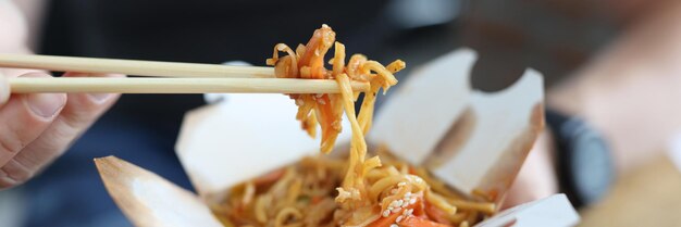 Hombre comiendo comida china con palillos de madera