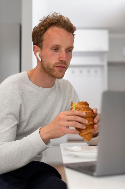 Hombre comiendo croissant plano medio