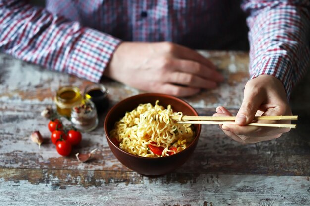 Hombre comiendo fideos con palillos. Fideos chinos.