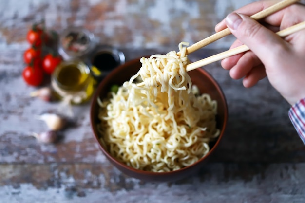 Hombre comiendo fideos con palillos. Fideos chinos.