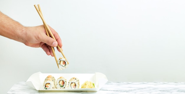 Hombre comiendo para llevar conjunto de sushi japonés, concepto de comida de entrega