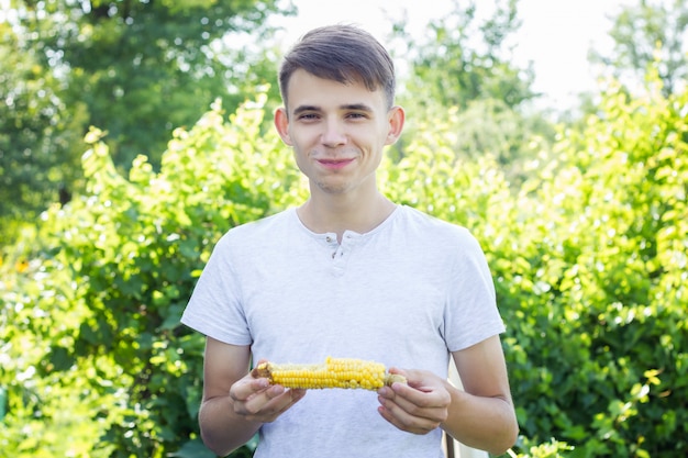 Hombre comiendo maíz cocido, el concepto vegetariano.