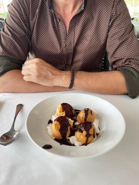 Hombre comiendo profiteroles en una mesa de restaurante