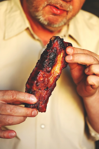 Hombre comiendo sabrosas costillas de cerdo a la parrilla