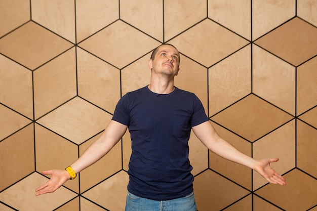 El hombre como una pose de santo en el fondo de madera en camiseta oscura.