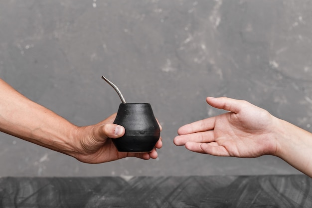 Un hombre compartiendo té de Yerba Mate en calabaza con paja de metal sorbida