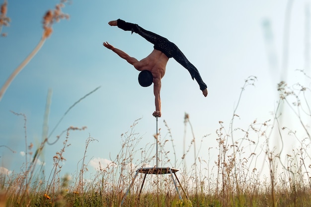 Un hombre de complexión atlética realiza complejos ejercicios de gimnasia en un campo