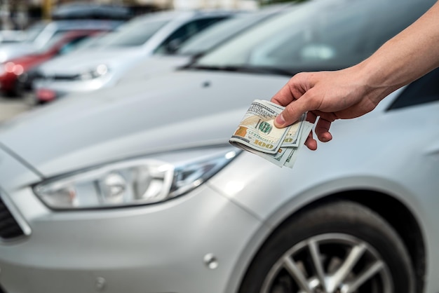 Hombre compra un auto moderno con dólar contra auto en la parte de atrás