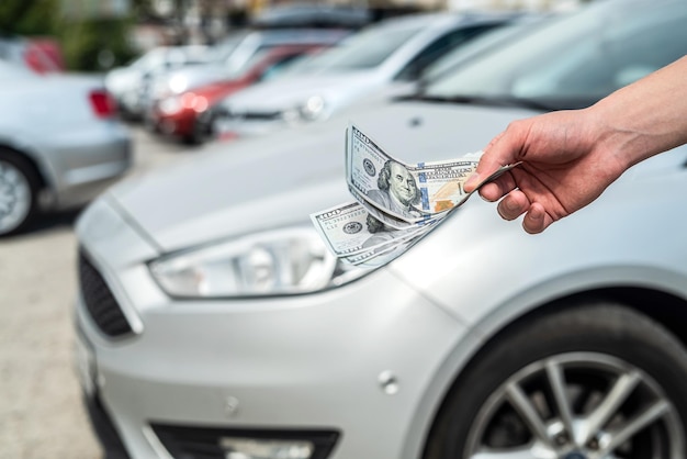 El hombre compra un automóvil moderno con un dólar contra un automóvil en concepto de venta trasera