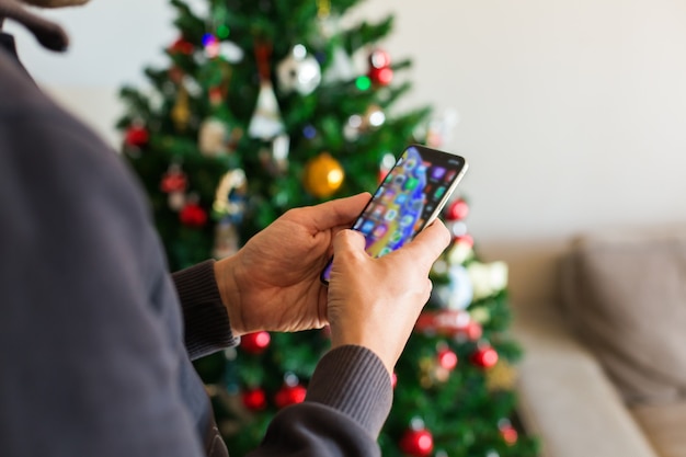 Hombre comprando regalos de Navidad año nuevo en línea con teléfono portátil